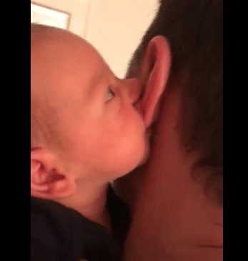 Vidéo d'un bébé dans les bras de son papa qui tète son lobe d'oreille